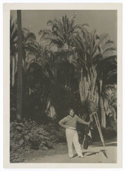 Item 0473. Eisenstein standing beside camera in front of large palm trees. Possibly taken near Tehuantepec.