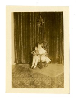 Child holding doll while sitting on chair