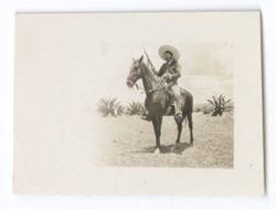 Item 0911. Unidentified man holding rifle on horseback.