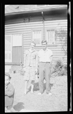 Martha Carmichael with an unidentified man, posing in front of a house.