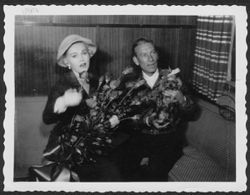 Hoagy Carmichael holding a dog and sitting beside an unidentified woman.