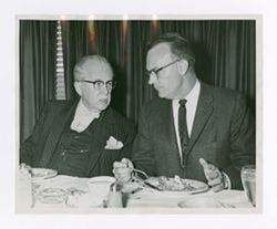 Roy Howard dining and talking with another man