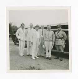Group of men standing in front of cars