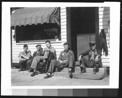 Five males seated in front of building